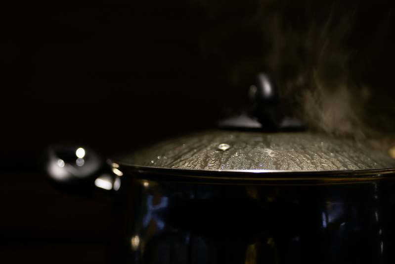 Two bloggers testing slow cookers in a home kitchen with notebooks and measuring tools